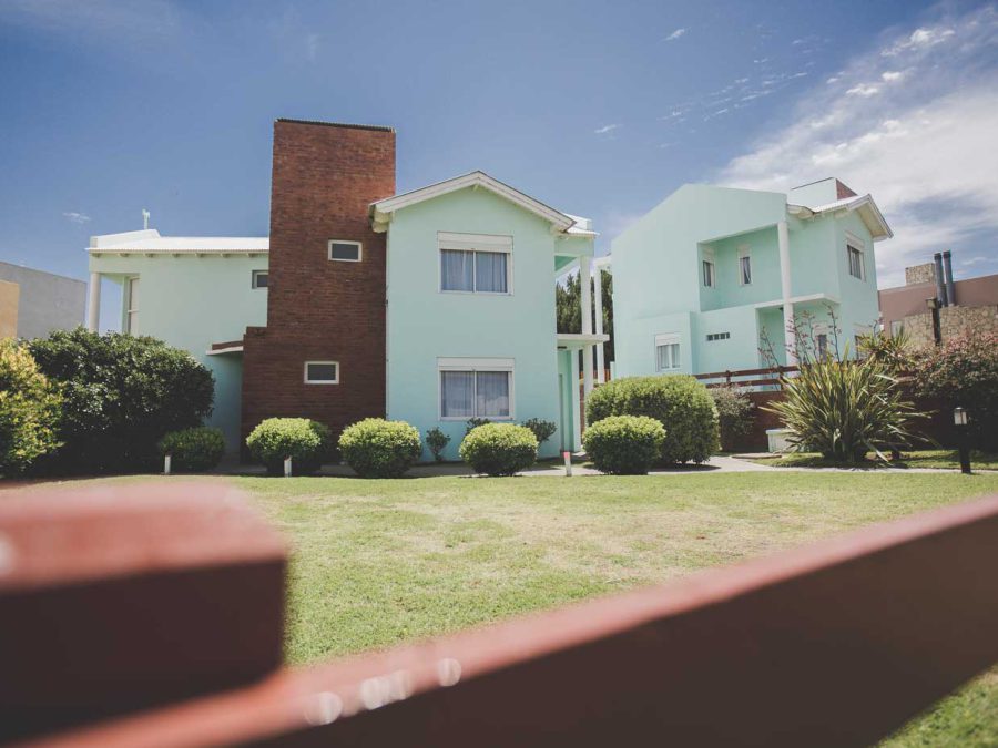Cabañas de dos plantas en verde agua con jardín y arbustos, Cabañas Los Prados