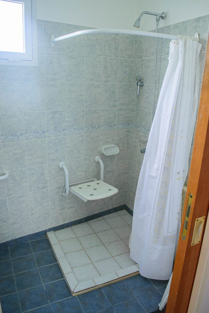 Ducha accesible de la cabaña, con asiento plegable, barras de apoyo y rociador de mano, Cabañas Los Prados